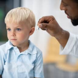 A doctor fits a little boy for a hearing aid.