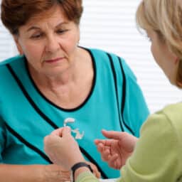 Audiologist explaining how hearing aids work to a female patient.
