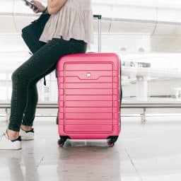 Woman sitting on her luggage as she waits in the airport.