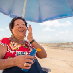 Happy woman putting sunscreen on at the beach