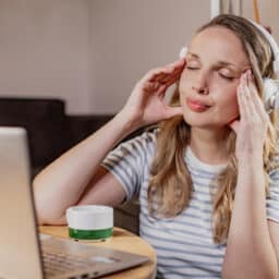 Tired woman rubbing her temples with headphones on