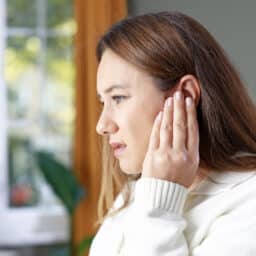 Young woman with tinnitus holding her ear