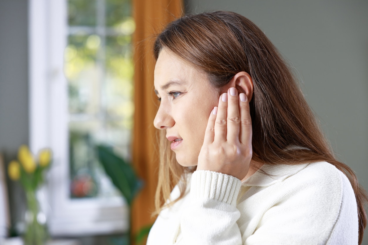 Young woman with tinnitus holding her ear.
