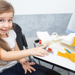 Little girl studies structure of human ear system in the audiologist's office