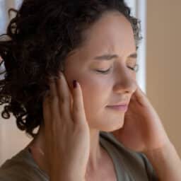 Woman holding her ears to block out tinnitus.