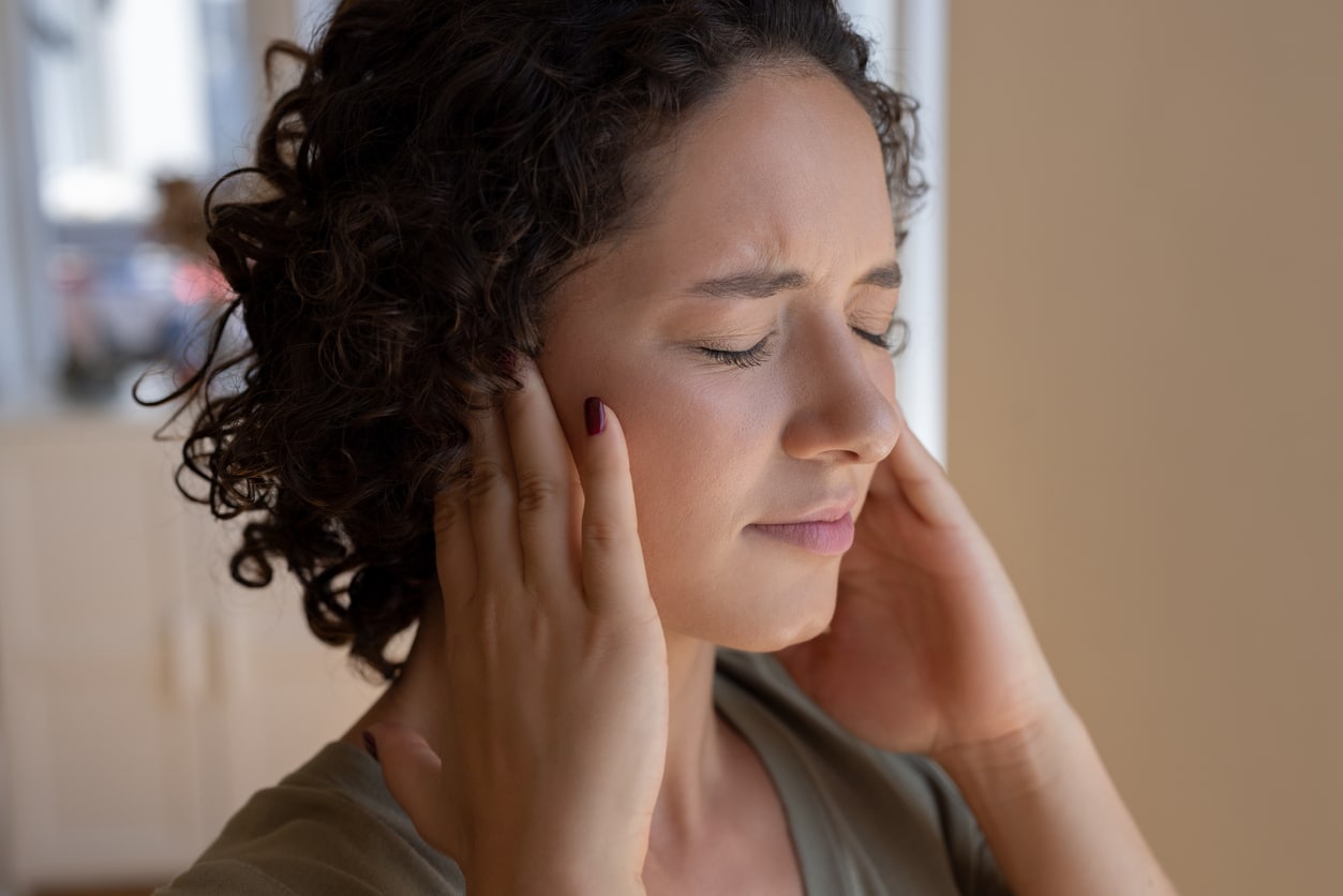 Woman holding her ears to block out tinnitus.