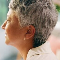 Close up of a senior woman wearing a behind-the-ear hearing aid.