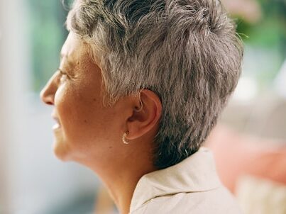 Close up of a senior woman wearing a behind-the-ear hearing aid.