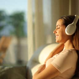 Woman resting listening to an audiobook with eyes closed at home.