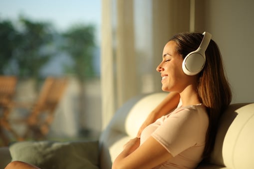 Woman resting listening to an audiobook with eyes closed at home.